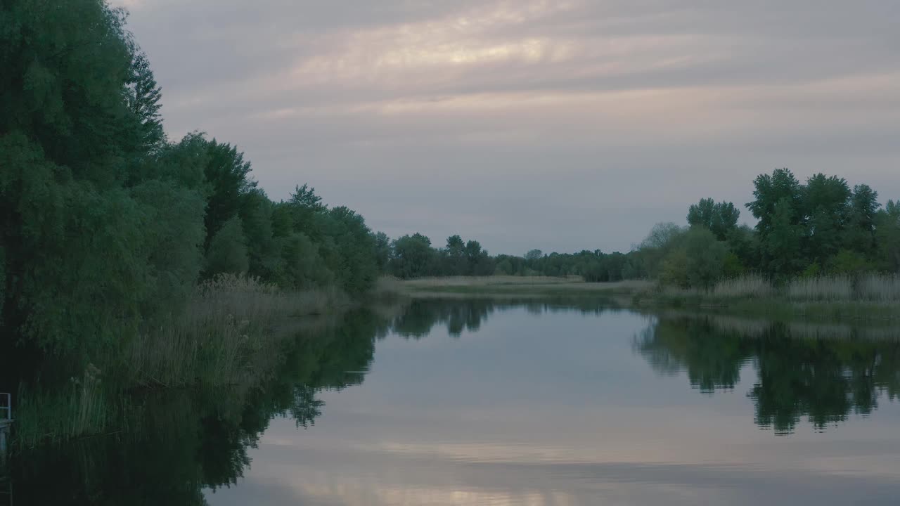 黄昏景观河无波。船浮在水面上，树长在岸边。美丽的云倒映在水中。视频素材