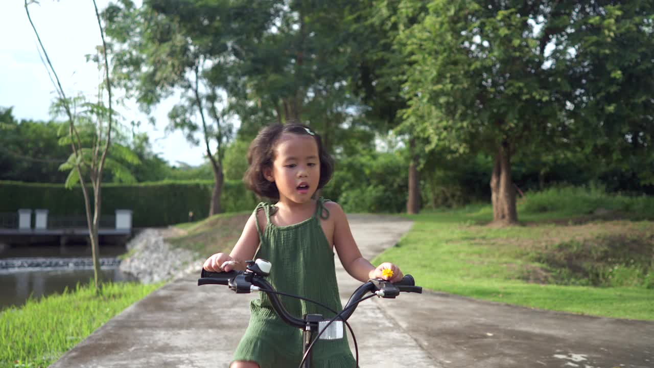 活泼可爱的小女孩在夏天骑着小自行车在公园。视频素材