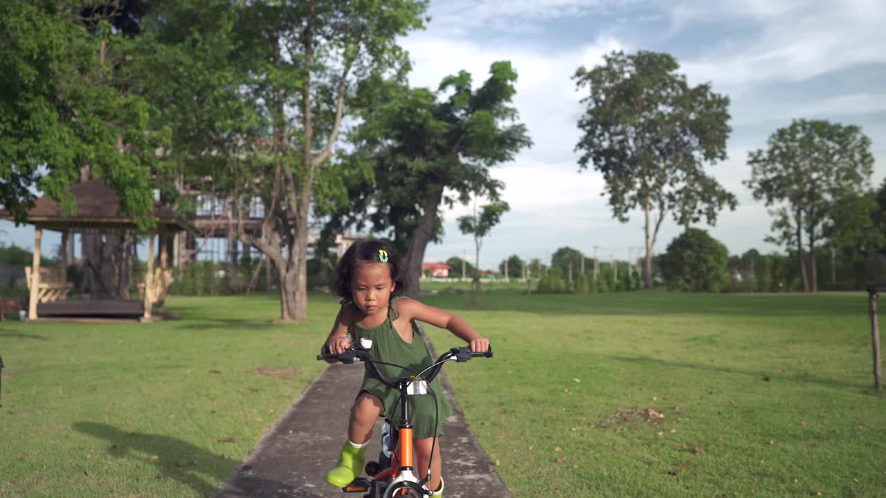 活泼的小女孩骑着小自行车在自行车道在公园。视频素材