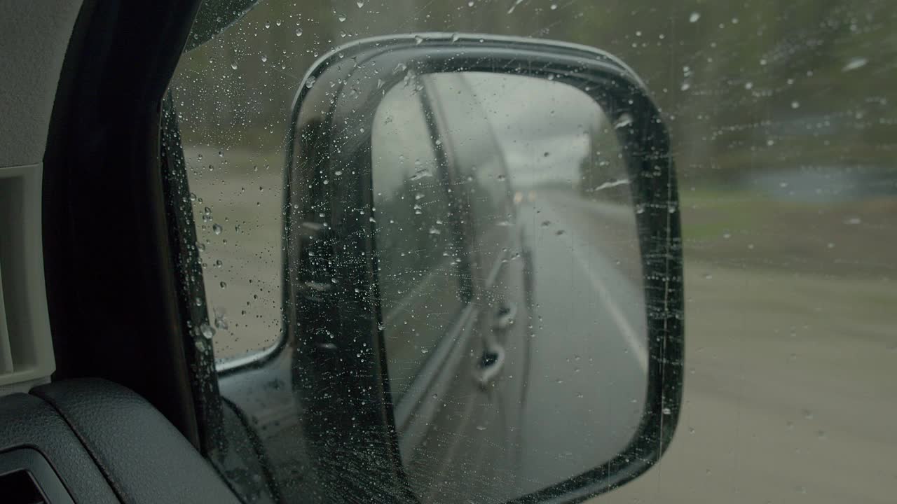 后视镜上的雨滴落在汽车挡风玻璃上。视频素材