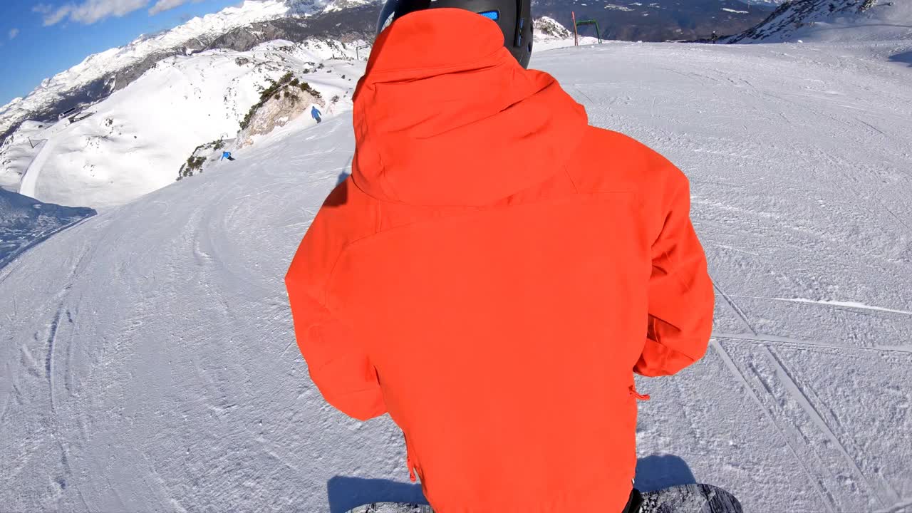 在一个阳光明媚的冬日，一名男子在滑雪胜地的斜坡上雕刻视频素材