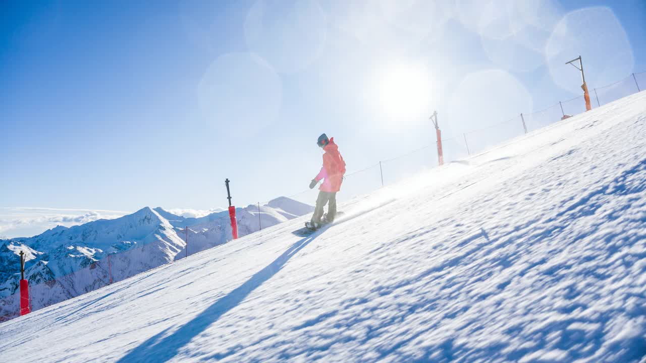 滑雪板运动员在滑雪道上滑行，在转弯时喷着雪，背景是山脉视频下载