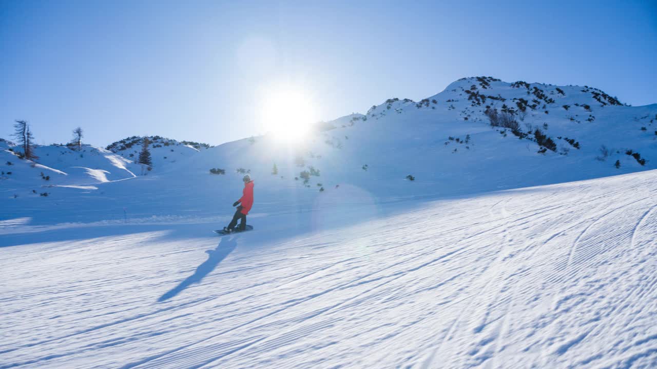 滑雪板在滑雪坡道上滑行，喷着雪，背景是山脉视频素材