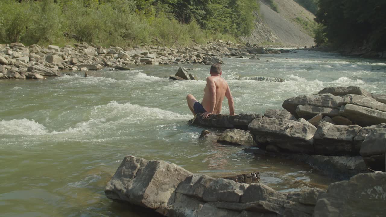 中年男性旅行者在暑假期间在崎岖的山间河流中游泳视频素材