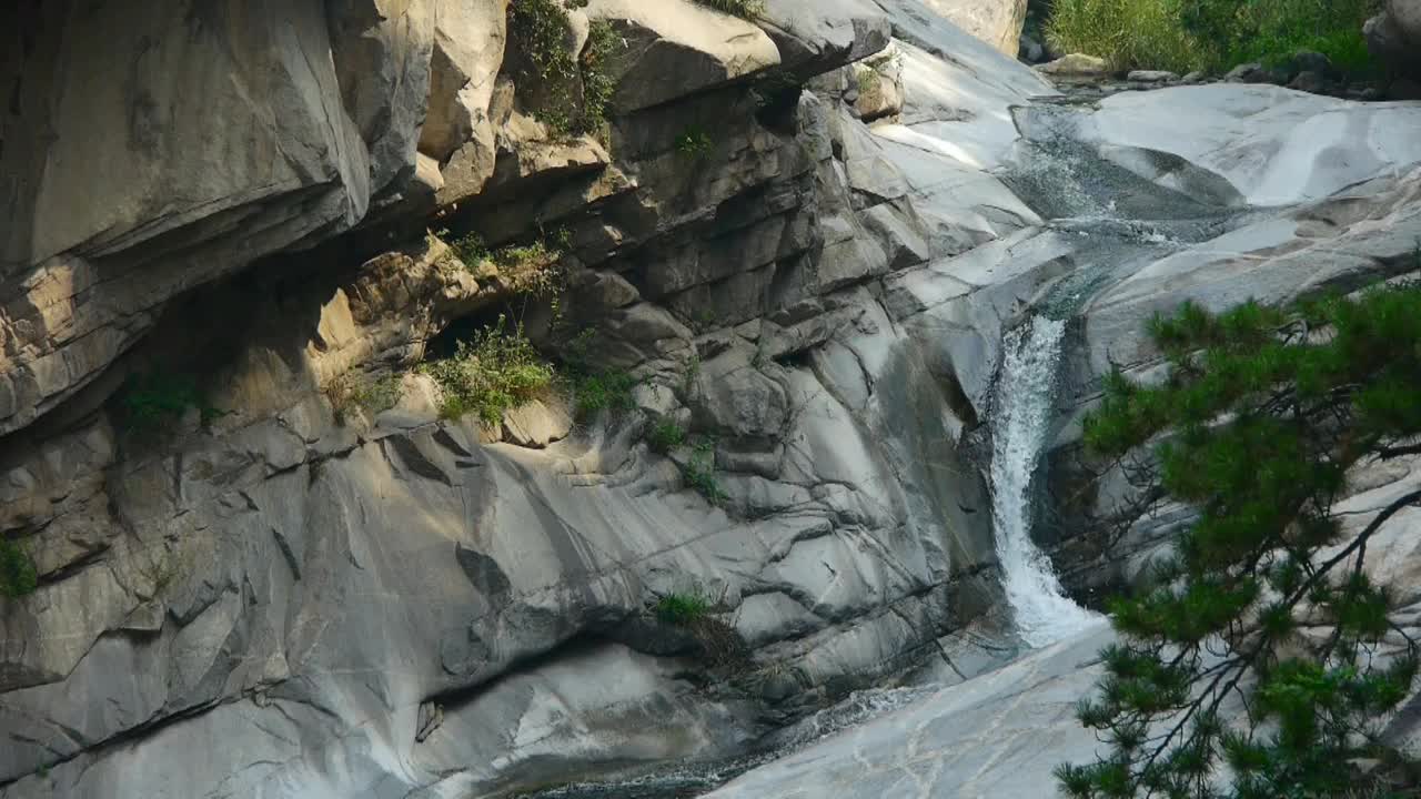 山间瀑布从多层石头，森林和灌木流进水池。视频素材