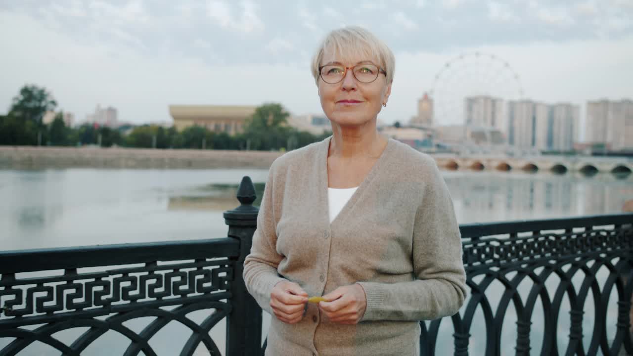 成熟女人慢动作肖像，带着幸福的微笑走在河堤上视频素材