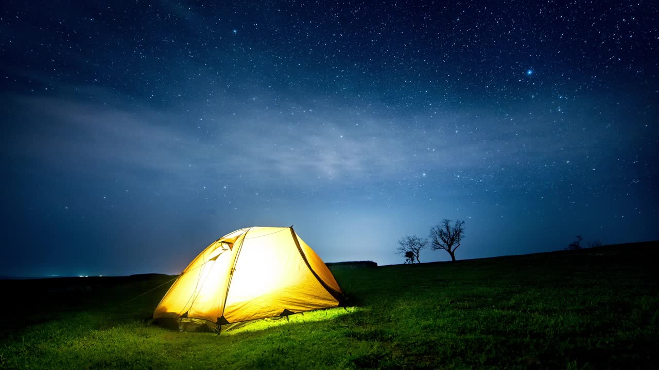 延时。发光的帐篷在夜晚的山峦下星星的足迹。视频素材