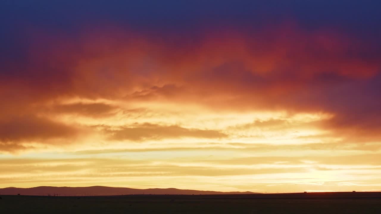 在五彩缤纷的夕阳中，车辆在远处的地平线上行驶视频素材