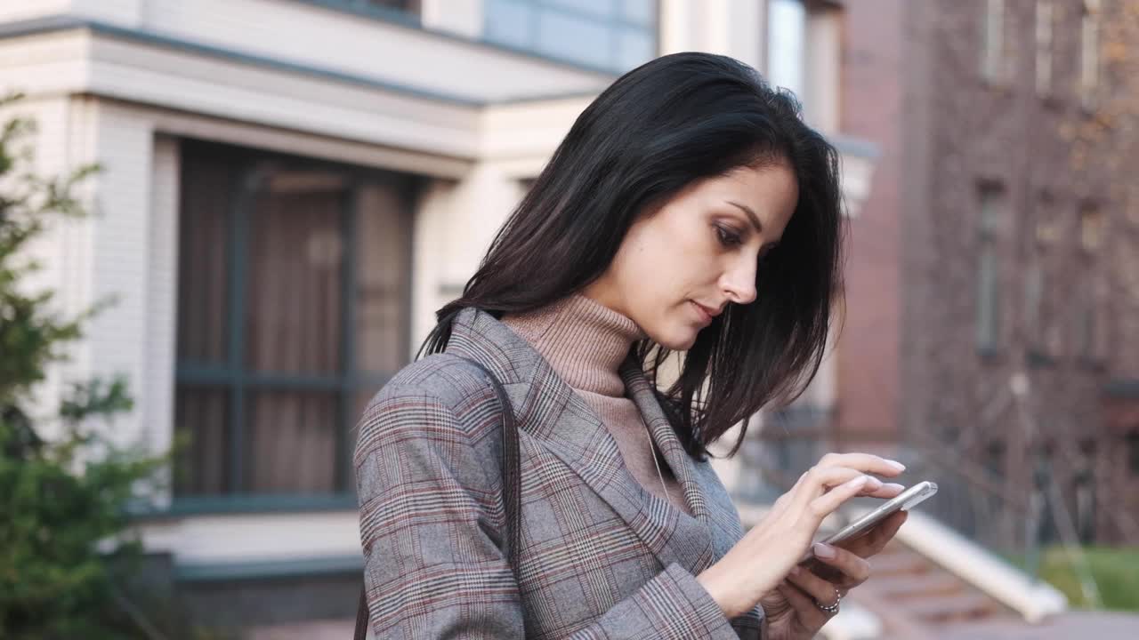 一位自信的商务女性在户外使用智能手机视频素材