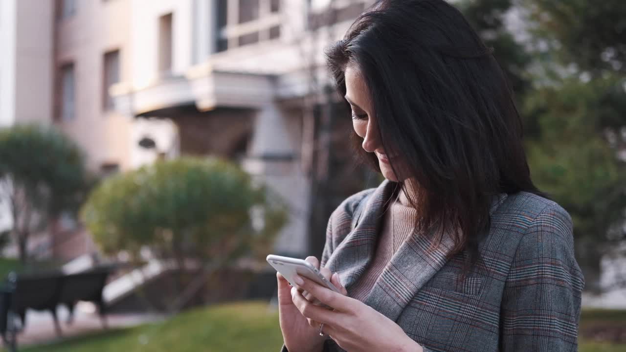 一位自信的商务女性在户外使用智能手机视频素材