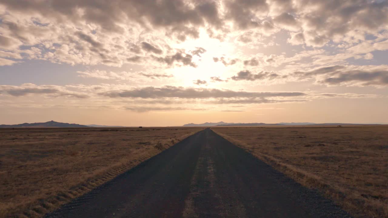 朝着太阳行驶在平坦广阔的犹他州沙漠的土路上视频素材