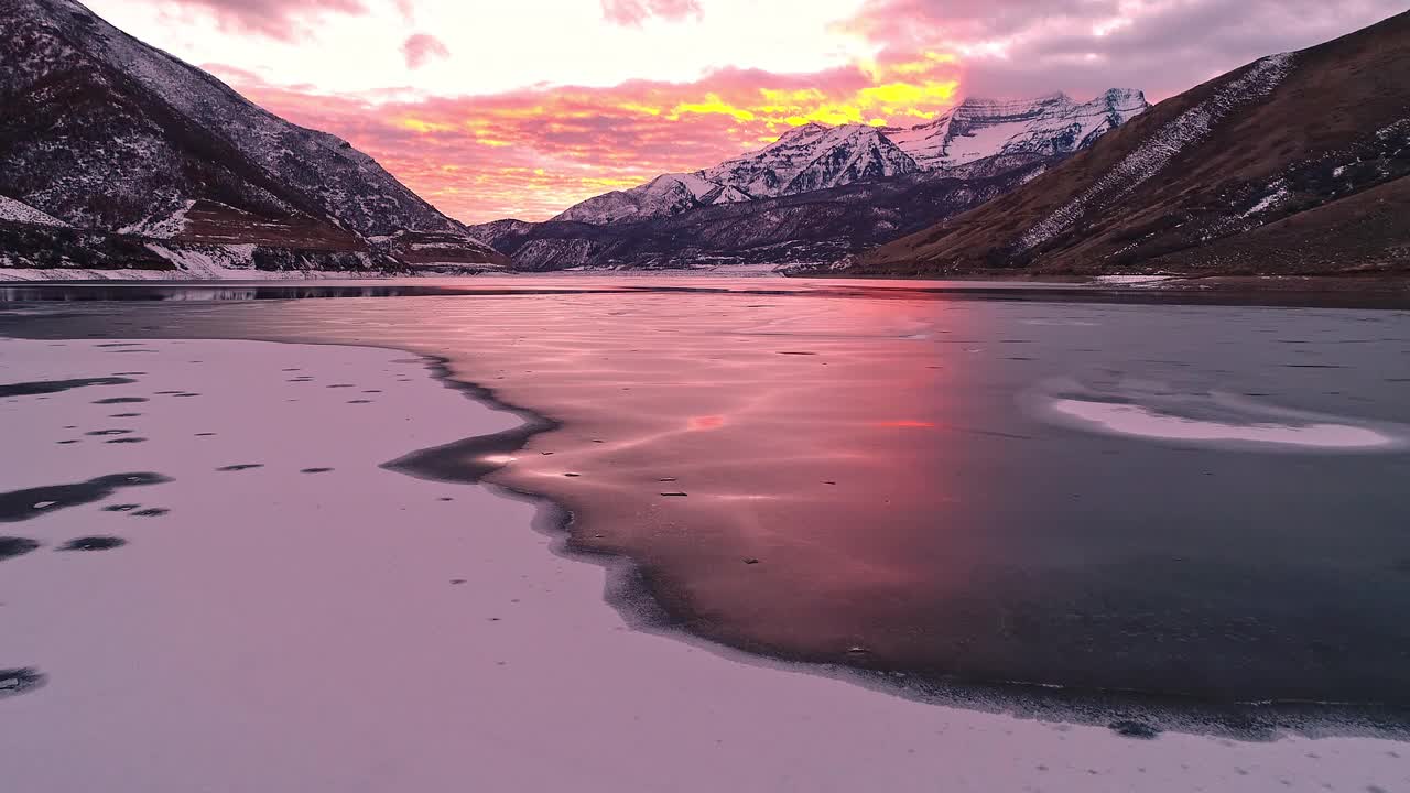 在五彩缤纷的夕阳中，飞越结冰的湖面上的冰雪视频素材