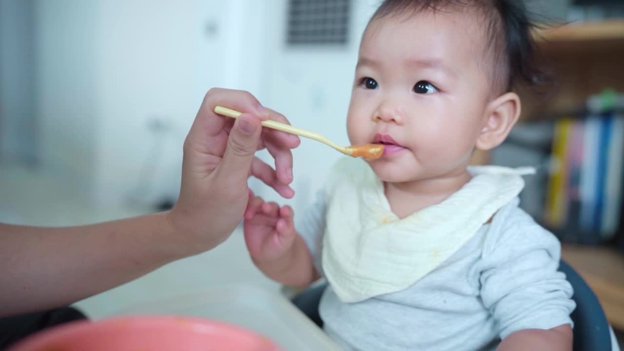 慢动作妈妈坐在家里的喂奶椅上喂女儿(4-7个月)视频素材