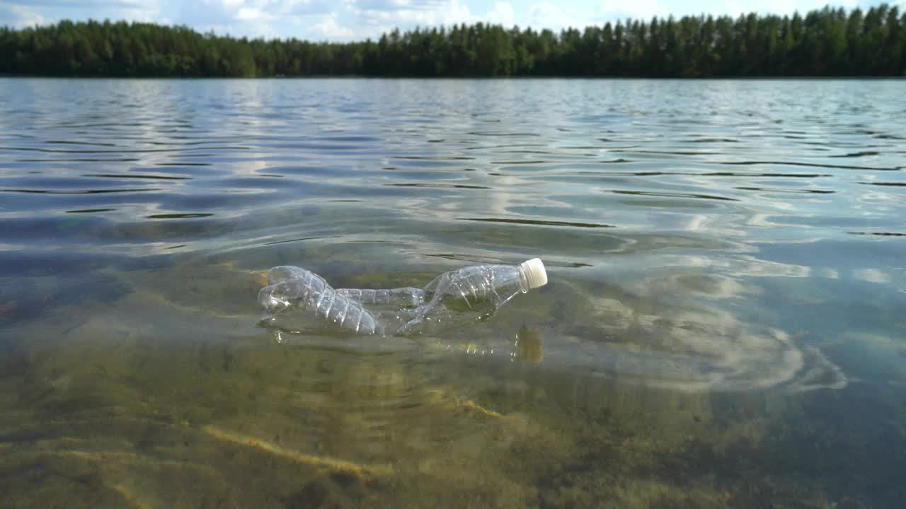 自然界中的塑料垃圾。用过的瓶子漂浮在水面上视频素材