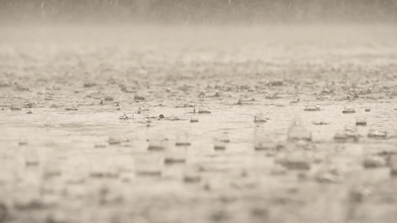 雨落在水泥地面上的水面上时，水滴形态的慢动作速度特写视频素材