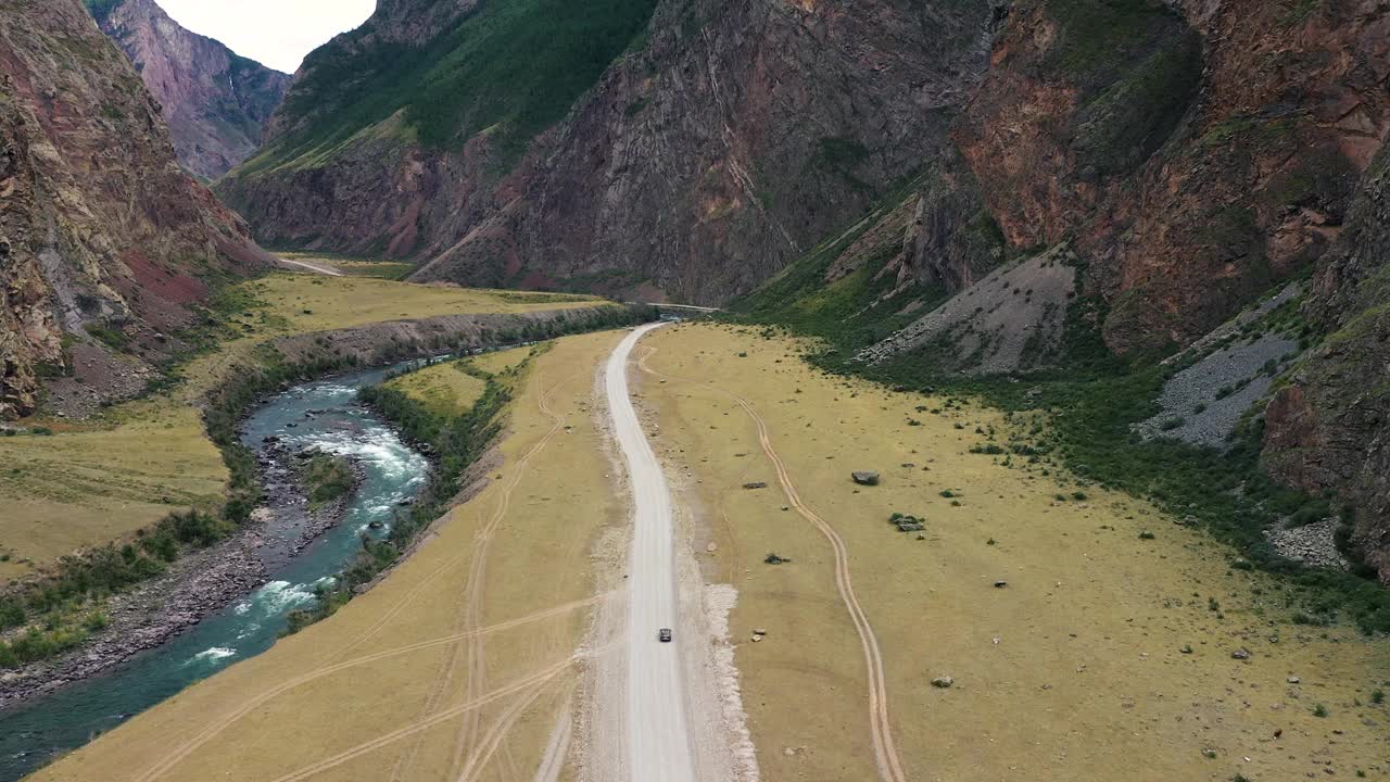 鸟瞰车行驶在山峡谷周围的岩石土路视频素材