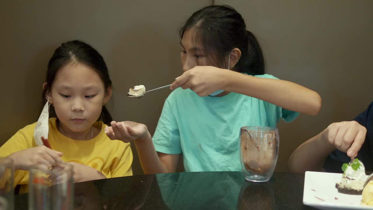 四个亚洲孩子一起在餐厅吃冰淇淋蛋糕庆祝生日，生活理念。视频素材