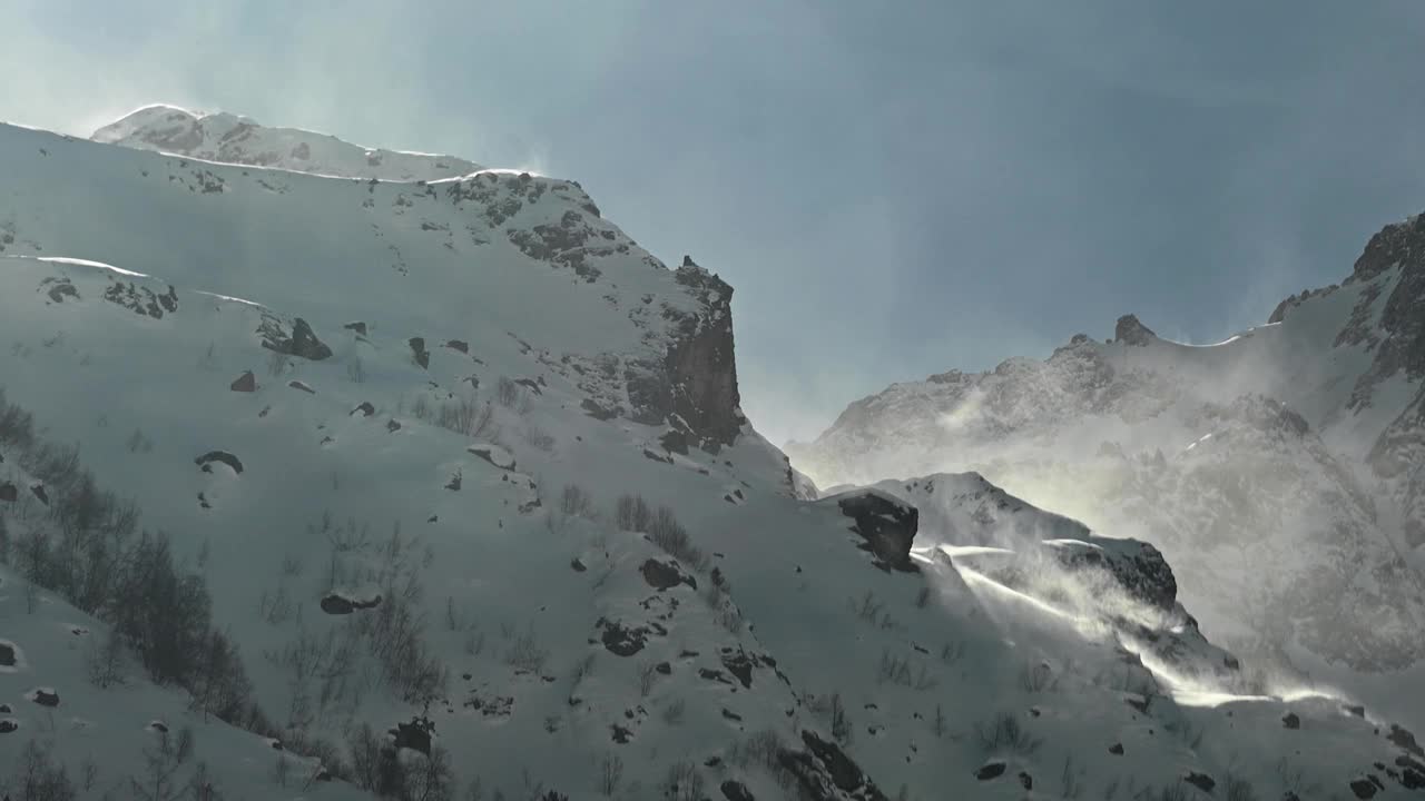 在长焦镜头上的时间流逝，高山的雪峰被风吹起的雪。山区恶劣的天气条件视频素材