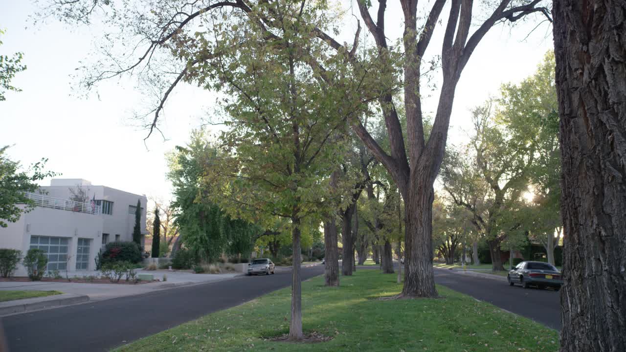 广角街道或道路，中间位置在上层或中产阶级居住区、社区或郊区。房屋可见。街上停着的汽车随处可见。视频素材