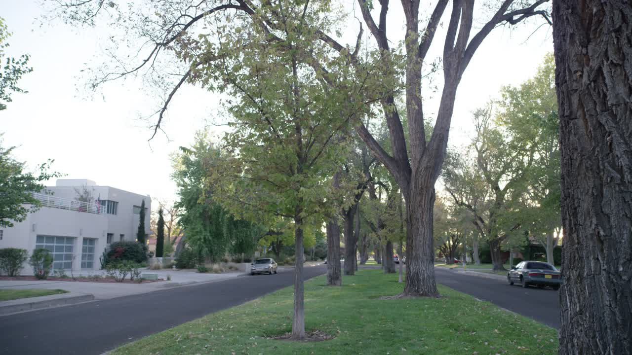 广角街道或道路，中间位置在上层或中产阶级居住区、社区或郊区。房屋可见。街上停着的汽车随处可见。视频素材