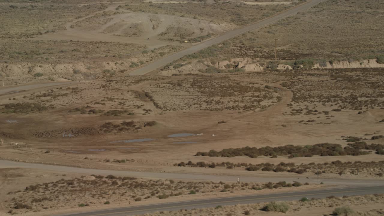 广角沙漠公路穿越平坦的沙漠地区。峡谷和灌木丛可见。视频素材