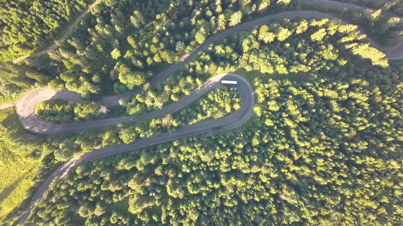 鸟瞰图的蜿蜒的道路与割草汽车和卡车在高山口，槽茂密的树林。视频素材