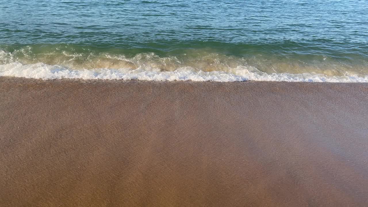 在阳光明媚的日子里，在空旷的海滩上欣赏美丽的海浪和沙滩。视频素材