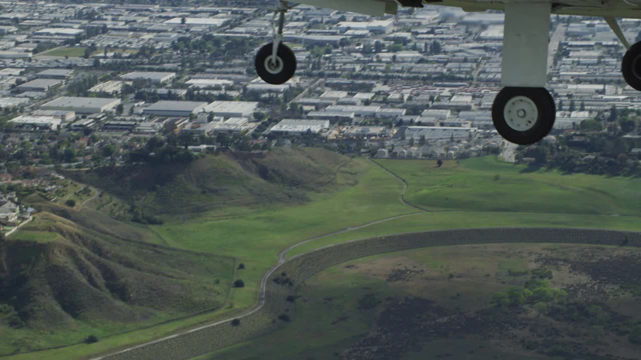 一架白色纳瓦霍小飞机在圣费尔南多谷上空飞行。山脉在bg可见。视频素材