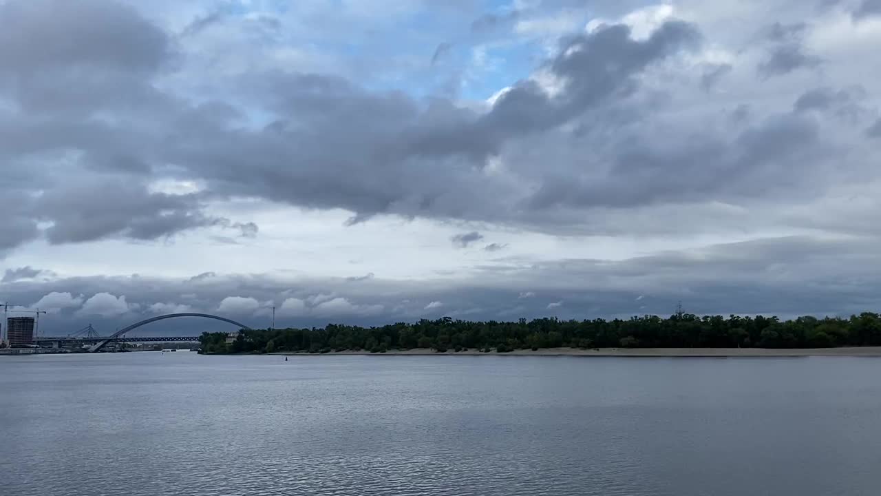 在寒冷的夜晚，云朵飘浮在闪闪发亮的河水上。穆迪秋天的天空。城市的天际线。视频素材