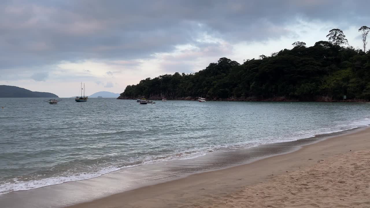 在多云的天空下，空旷的海滩上看到美丽的海浪和沙滩。视频素材