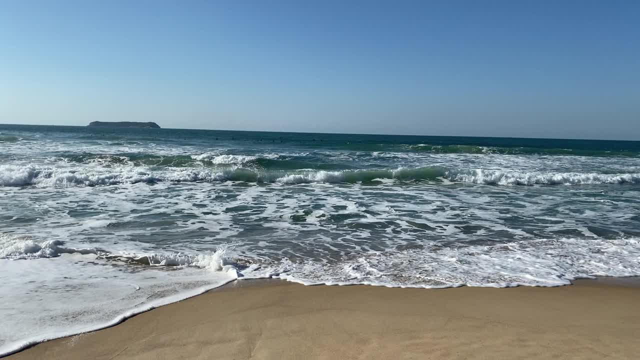 在阳光明媚的日子里，在空旷的海滩上欣赏美丽的海浪和沙滩。视频素材