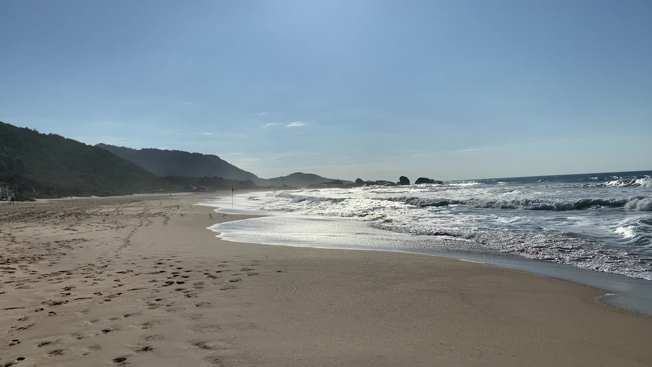 在阳光明媚的日子里，在空旷的海滩上欣赏美丽的海浪和沙滩。视频素材