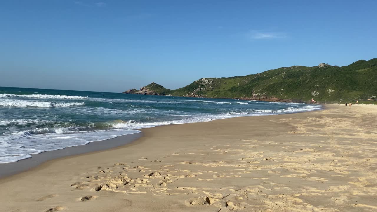 在阳光明媚的日子里，在空旷的海滩上欣赏美丽的海浪和沙滩。视频素材