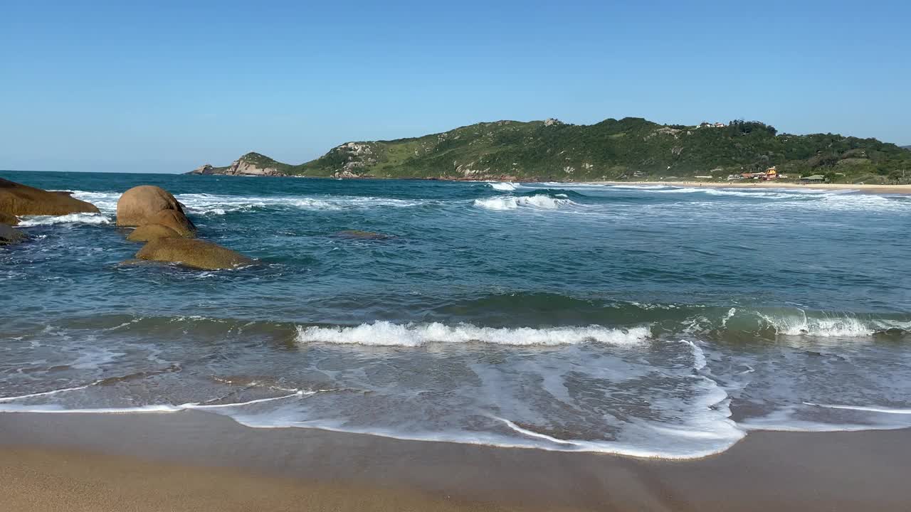 在阳光明媚的日子里，在空旷的海滩上欣赏美丽的海浪和沙滩。视频素材