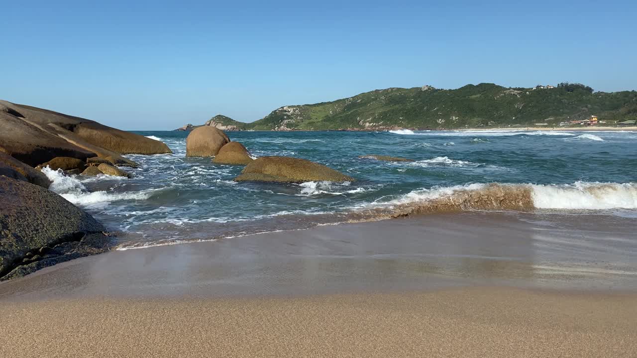 在阳光明媚的日子里，在空旷的海滩上欣赏美丽的海浪和沙滩。视频素材