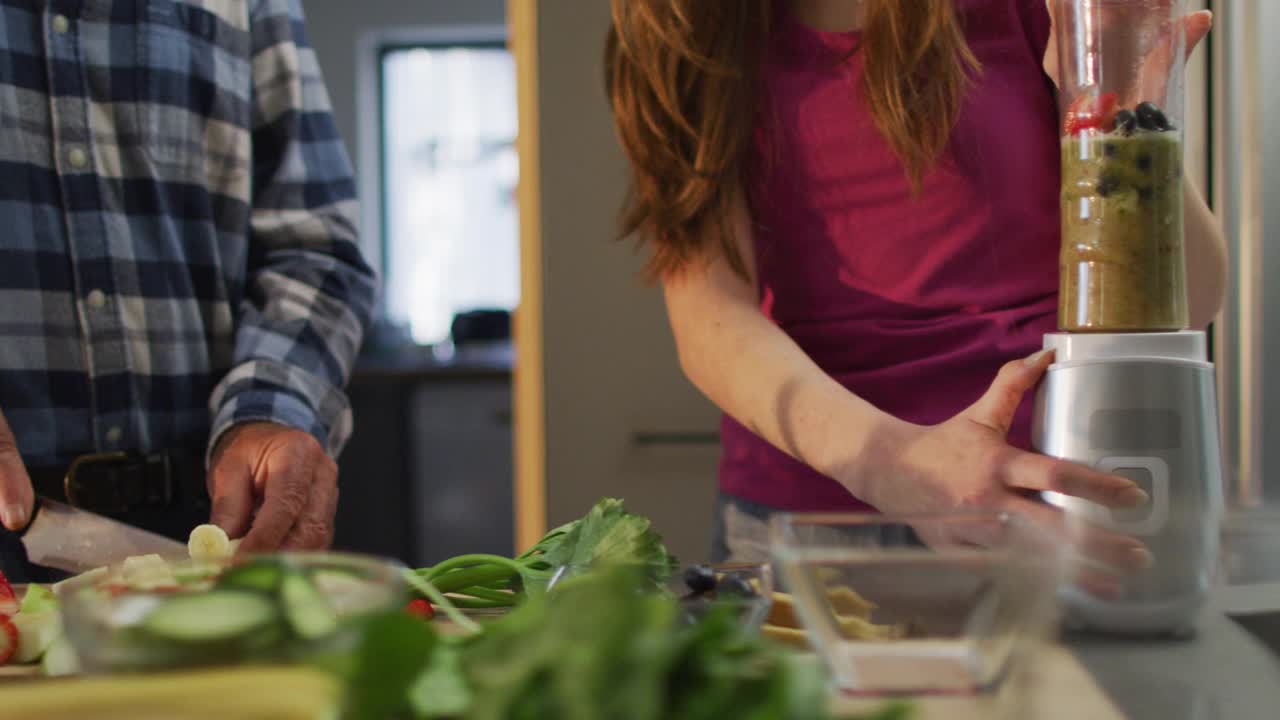 白种人父亲和十几岁的女儿在厨房准备健康饮料视频素材