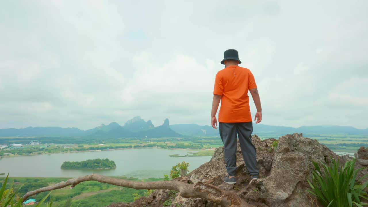 健康的亚洲男孩徒步上山，欣赏泰国岛上的风景，享受以山和树为背景的自然景观的和平和安静视频素材