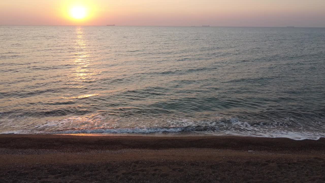 日出在海边的沙滩上。橘黄色的太阳在多云的天空。海滨度假视频素材