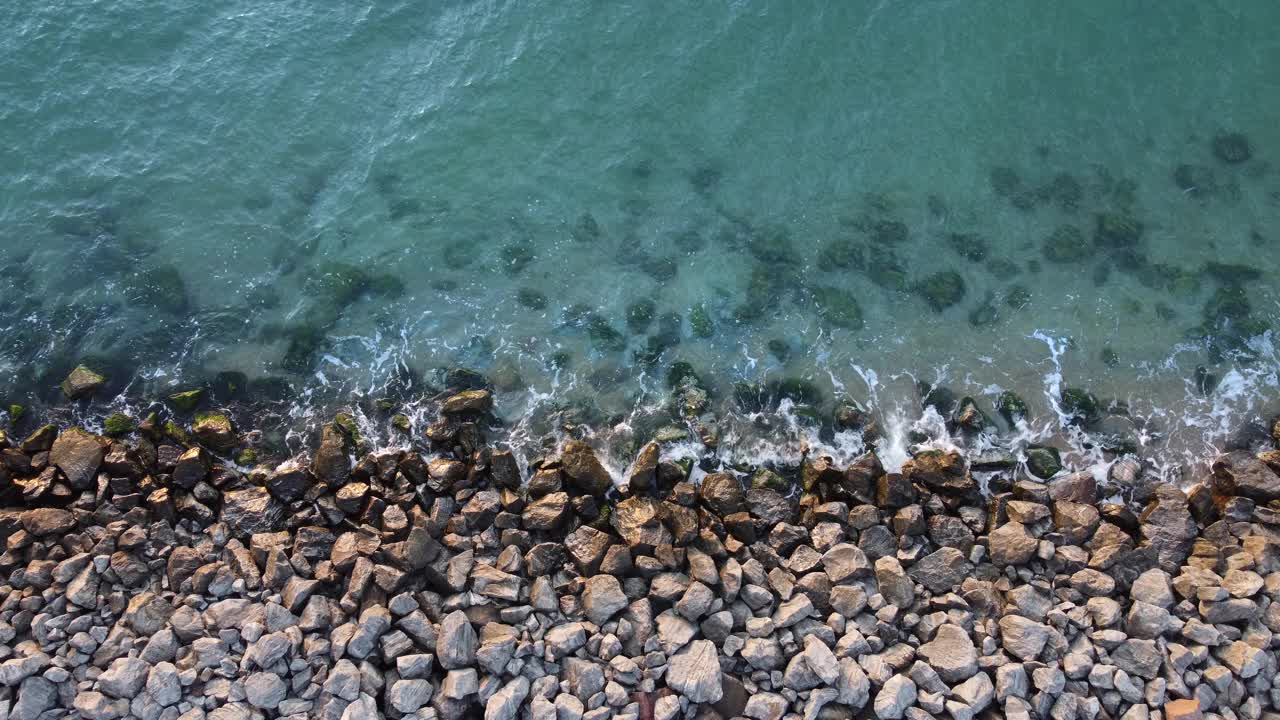 海岸上的石头冲刷着蓝色的大海。视频素材