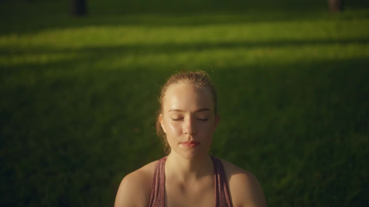 年轻女子闭着眼睛聚精会神地举起双手，慢慢呼吸，练瑜伽视频素材