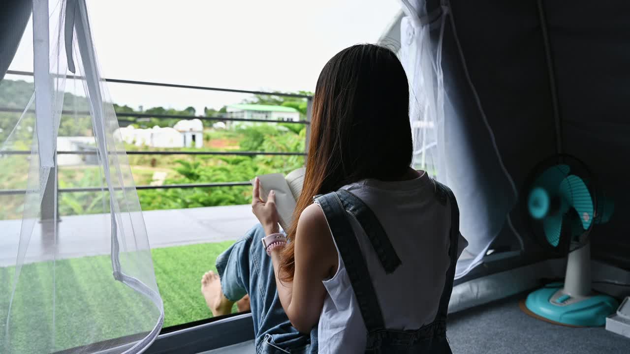 雨天，亚洲女人从帐篷里走出来，走到阳台上欣赏大自然视频素材