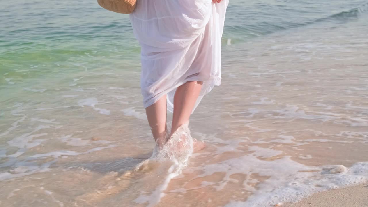 这名女子赤脚走在海边的双腿特写镜头视频素材