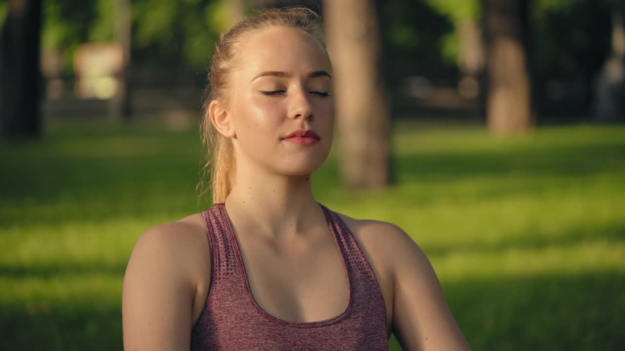 年轻放松的女子坐在莲花的位置闭上眼睛和开放的心灵视频素材