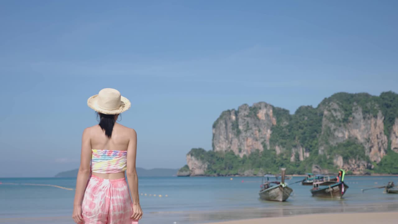 夏日岛屿海滩吹着风在旅行冒险旅行鼓舞人心的旅行呼吸新鲜的空气氧气，夏天的时候。女人的头发随风飘动。亚洲女士戴草帽享受假期视频素材