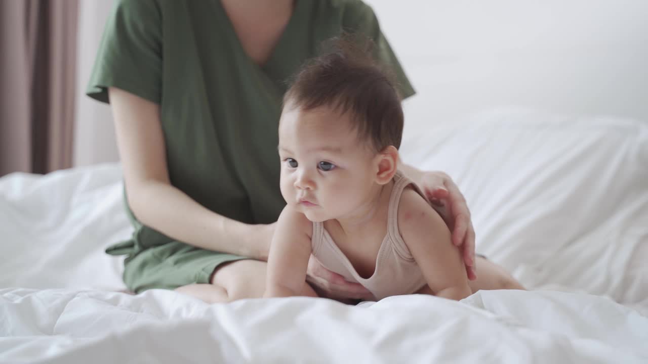 亚洲妇女母亲在卧室的床上玩婴儿婴儿蹒跚学步。天真宝贝与父母家庭关系良好。孩子在向妈妈学习的时候笑得很开心。视频素材