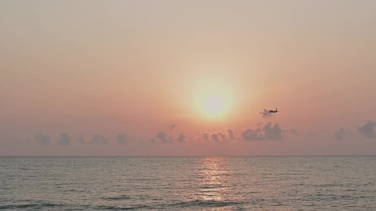 飞机在海上日落时起飞或降落，飞机在夕阳的光线下飞行，夏季空中旅行的概念。视频素材