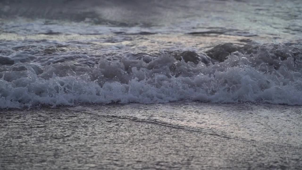 带着白色泡沫的狂暴海浪在卵石滩上翻滚。视频素材