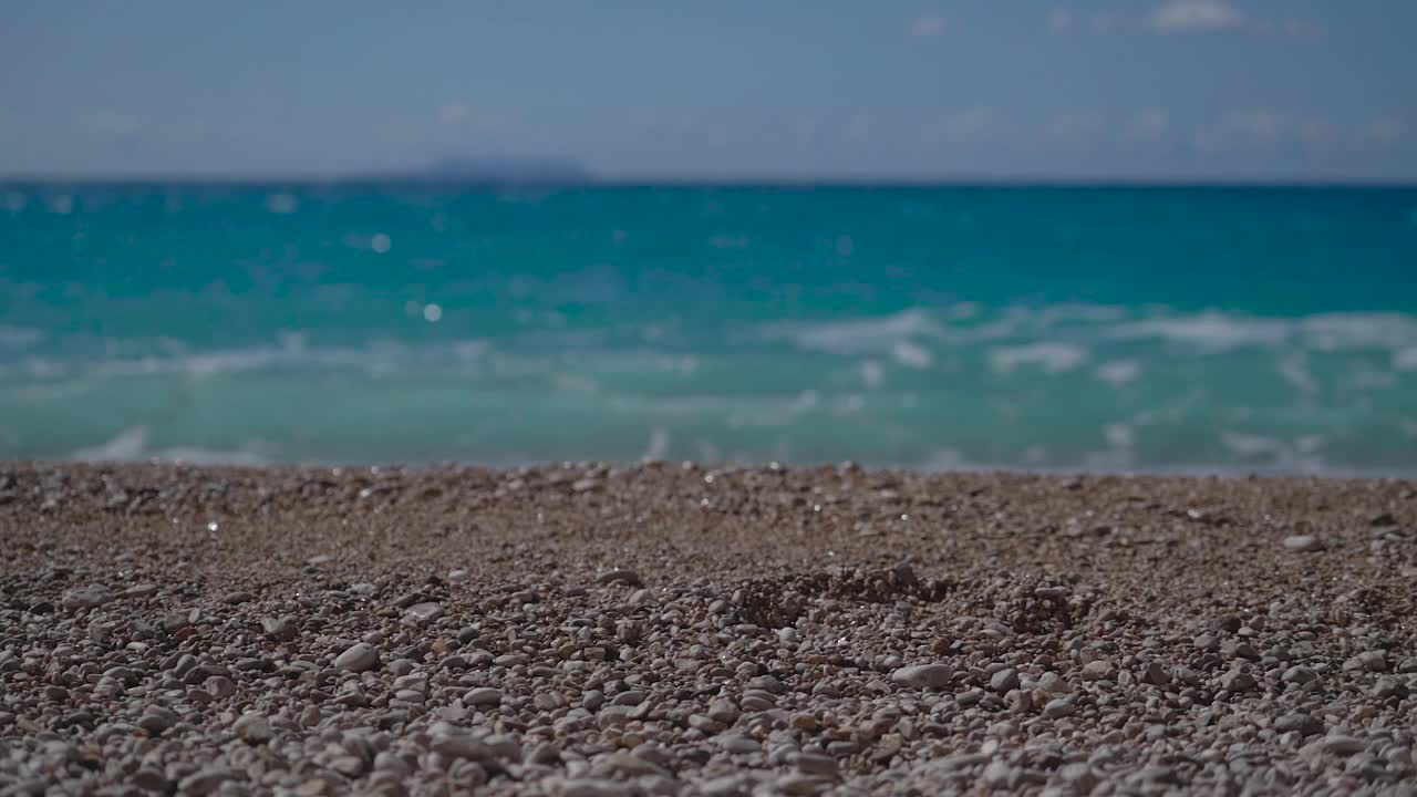 男人的腿在沙滩上走着，海水的波浪带着泡沫。视频素材