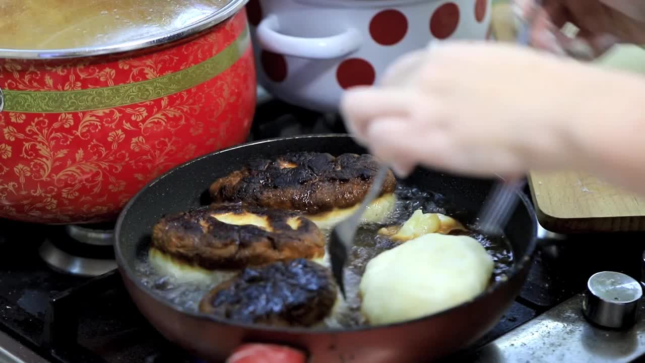 用土豆填充的馅饼，女人的手放在煎锅里滚烫的油里视频素材