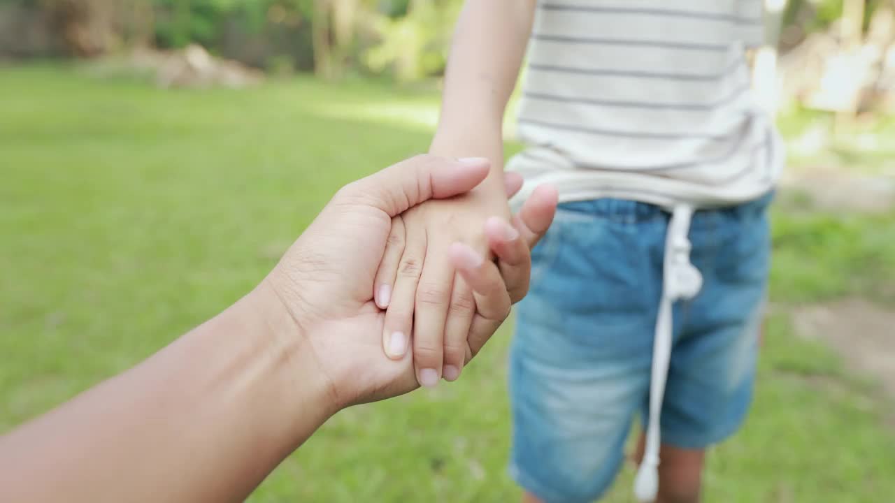 站在后院，母亲牵着孩子的手，靠近她。亚洲母亲和女儿互相关爱。幸福家庭生活理念。视频素材